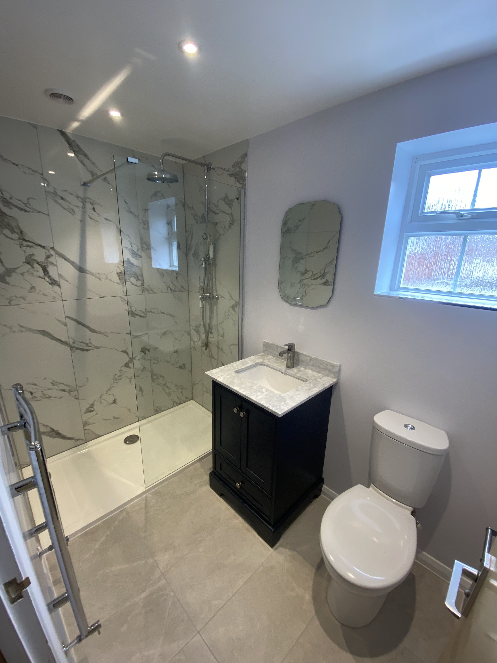 Shower room with a walk-in tray, navy vanity unit and ladder towel rail