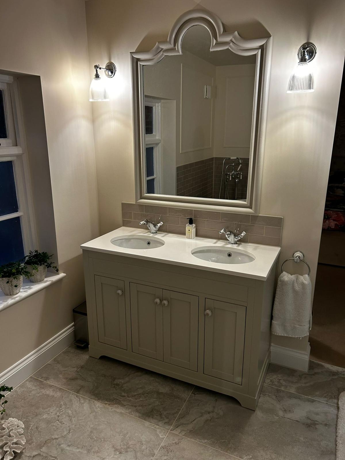 Double basin vanity unit with an ornate mirror and wall lights